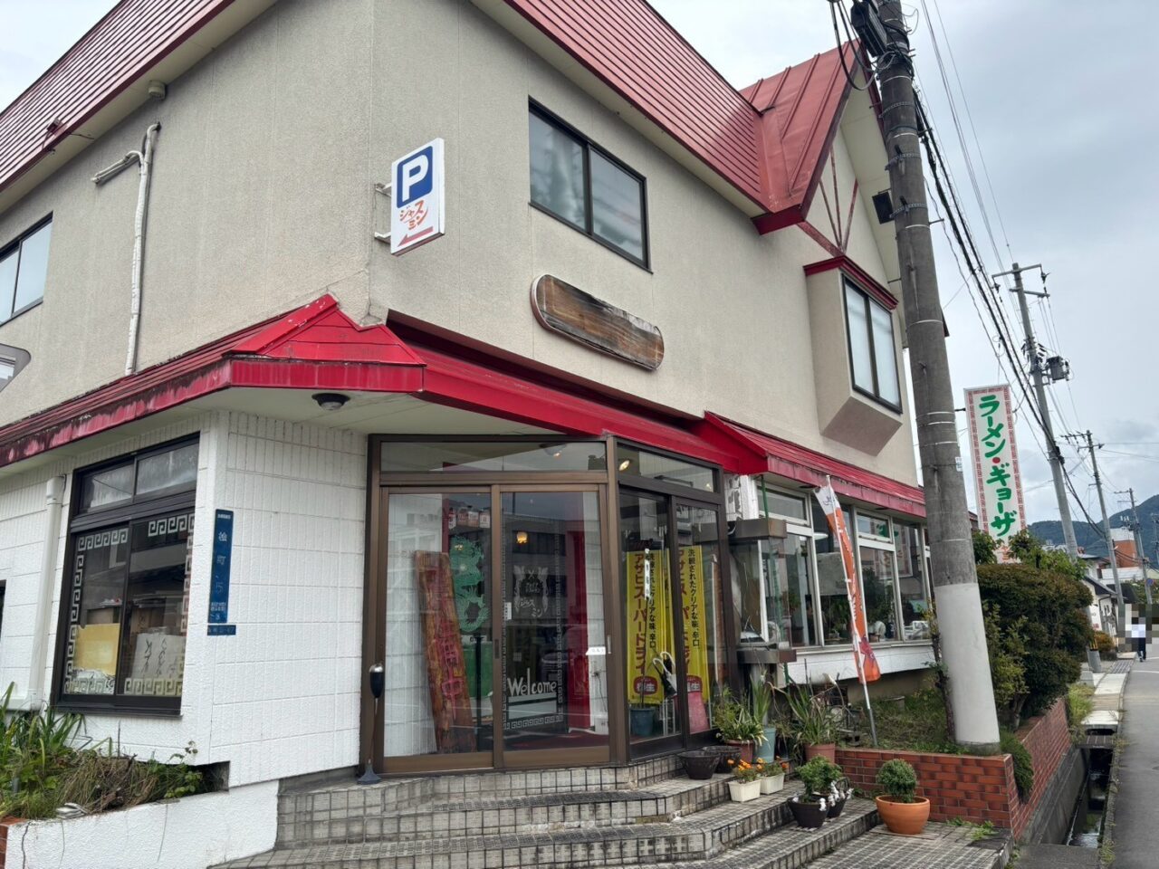 赤い屋根と「ラーメン・ギョーザ」の看板が目印のジャスミンの外観