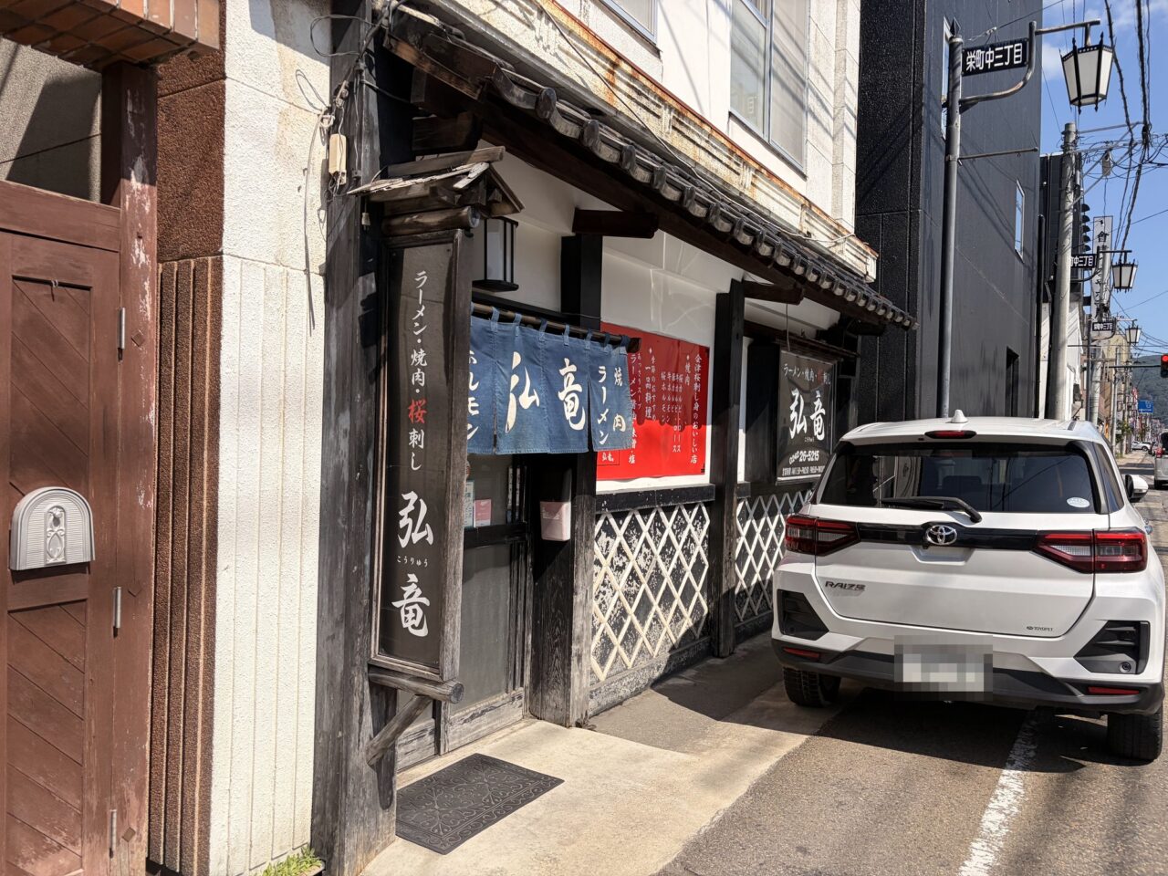 藍色ののれんと縦看板が掛かる弘竜の店舗外観