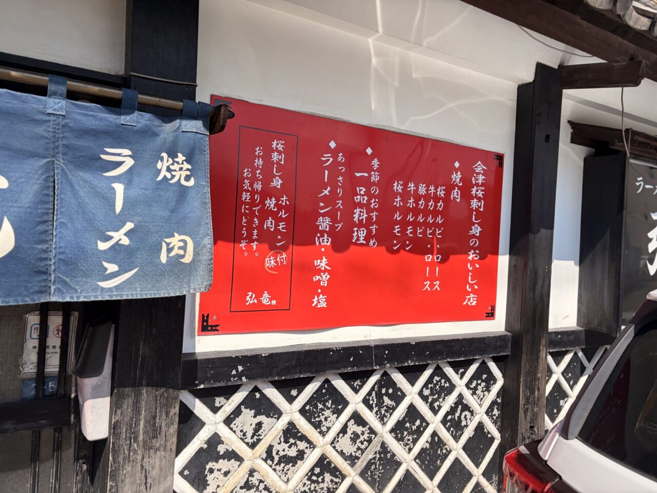 会津桜刺し身のおいしい店と書かれた弘竜の店頭の赤い案内板