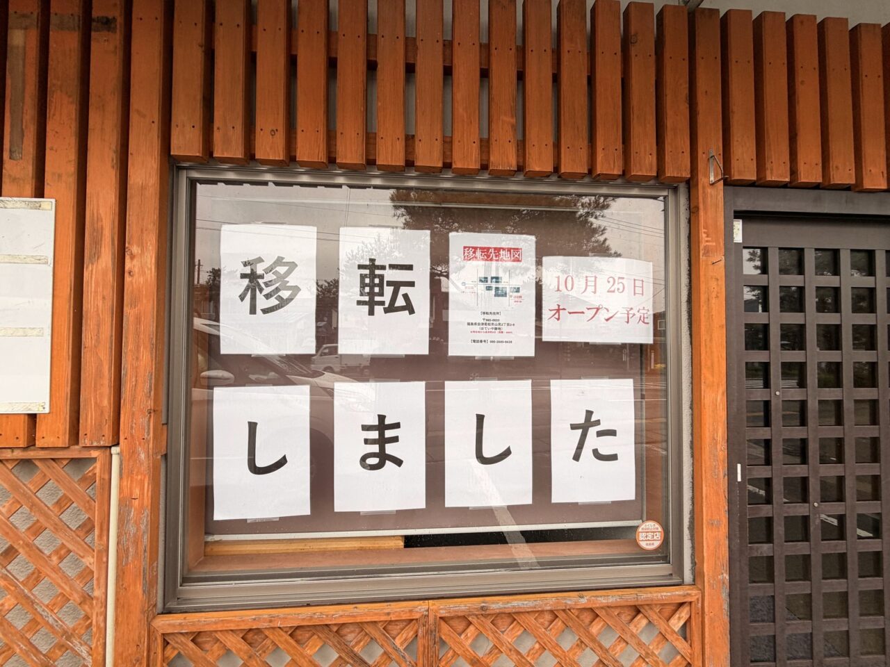 旧店舗の窓に掲示された「移転しました」の文字と10月25日オープン予定の案内