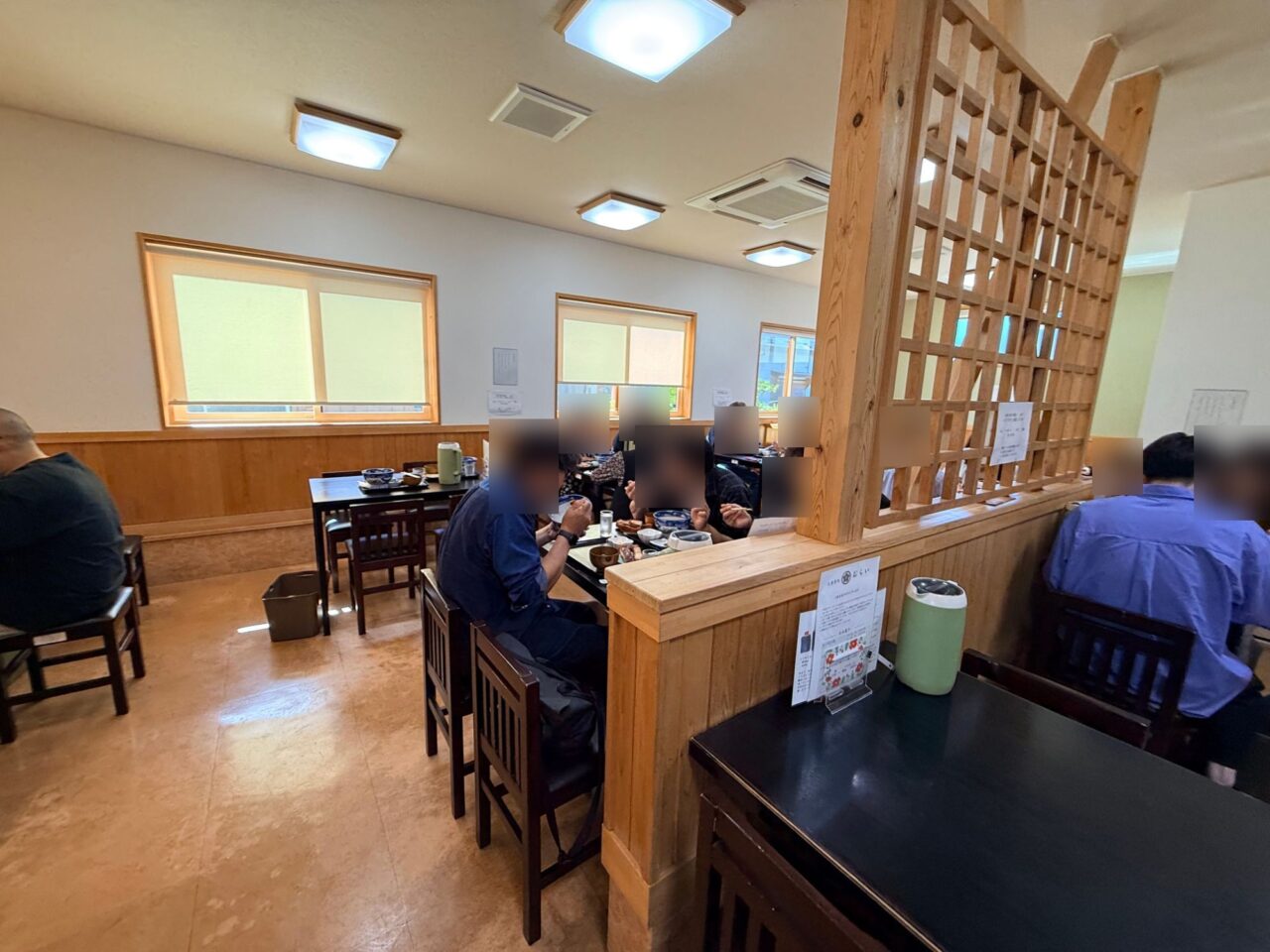 木の格子の仕切りとテーブル席が並ぶお食事処むらいの店内