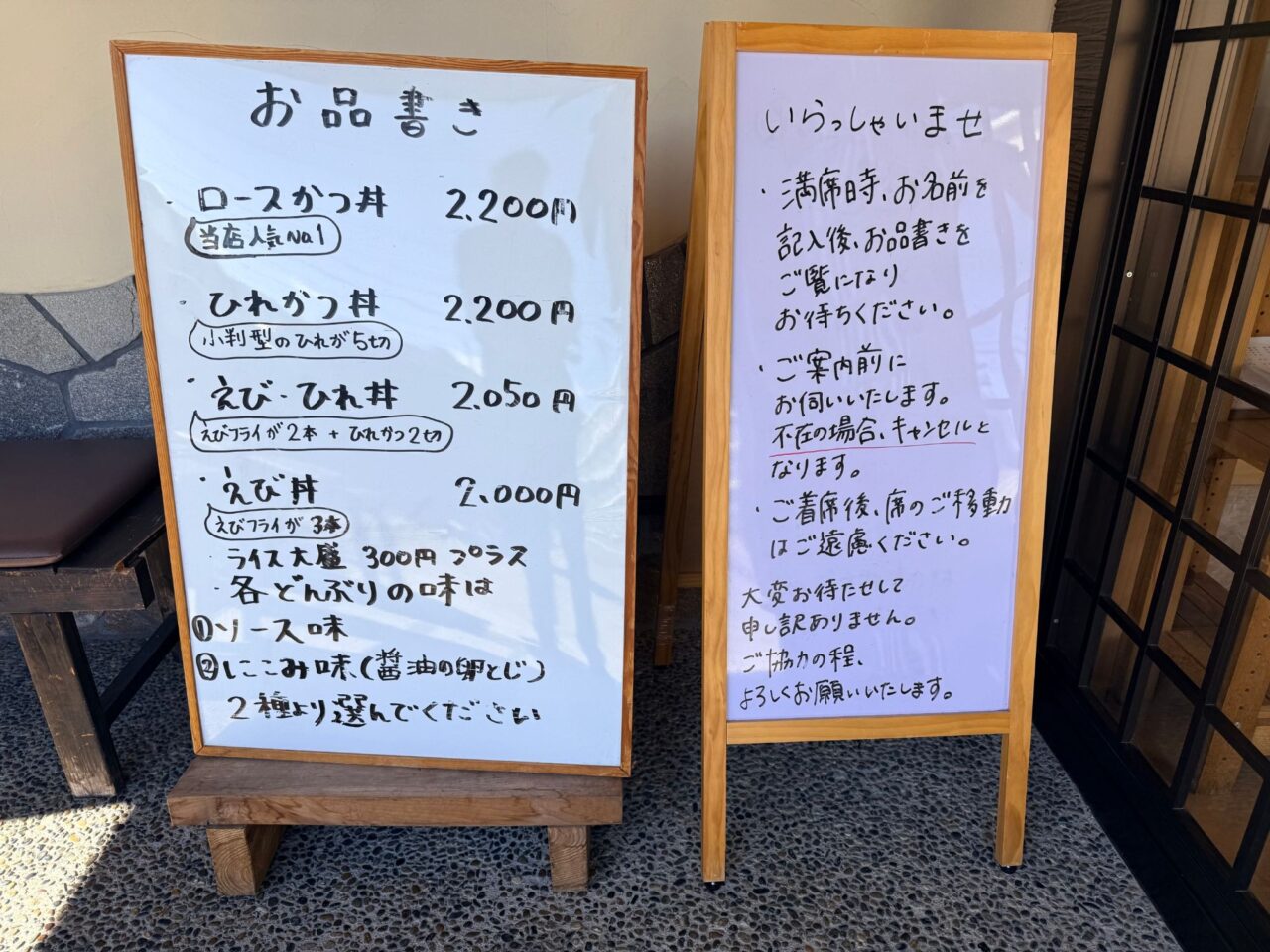 入口前に置かれたお品書きと満席時の案内が書かれたボード