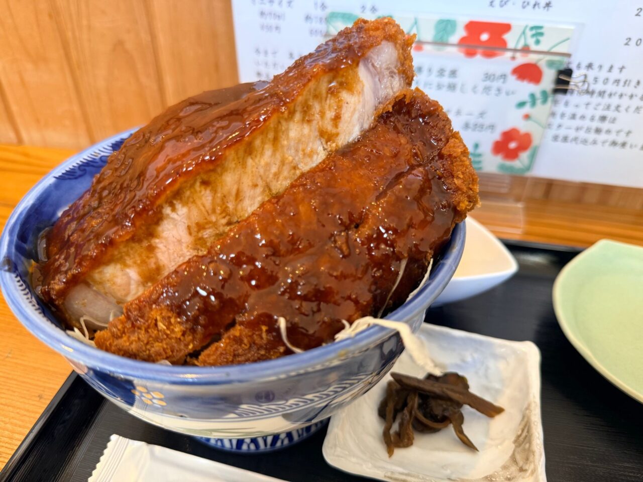 丼からはみ出すほど厚切りのロースかつにソースがかかったかつ丼