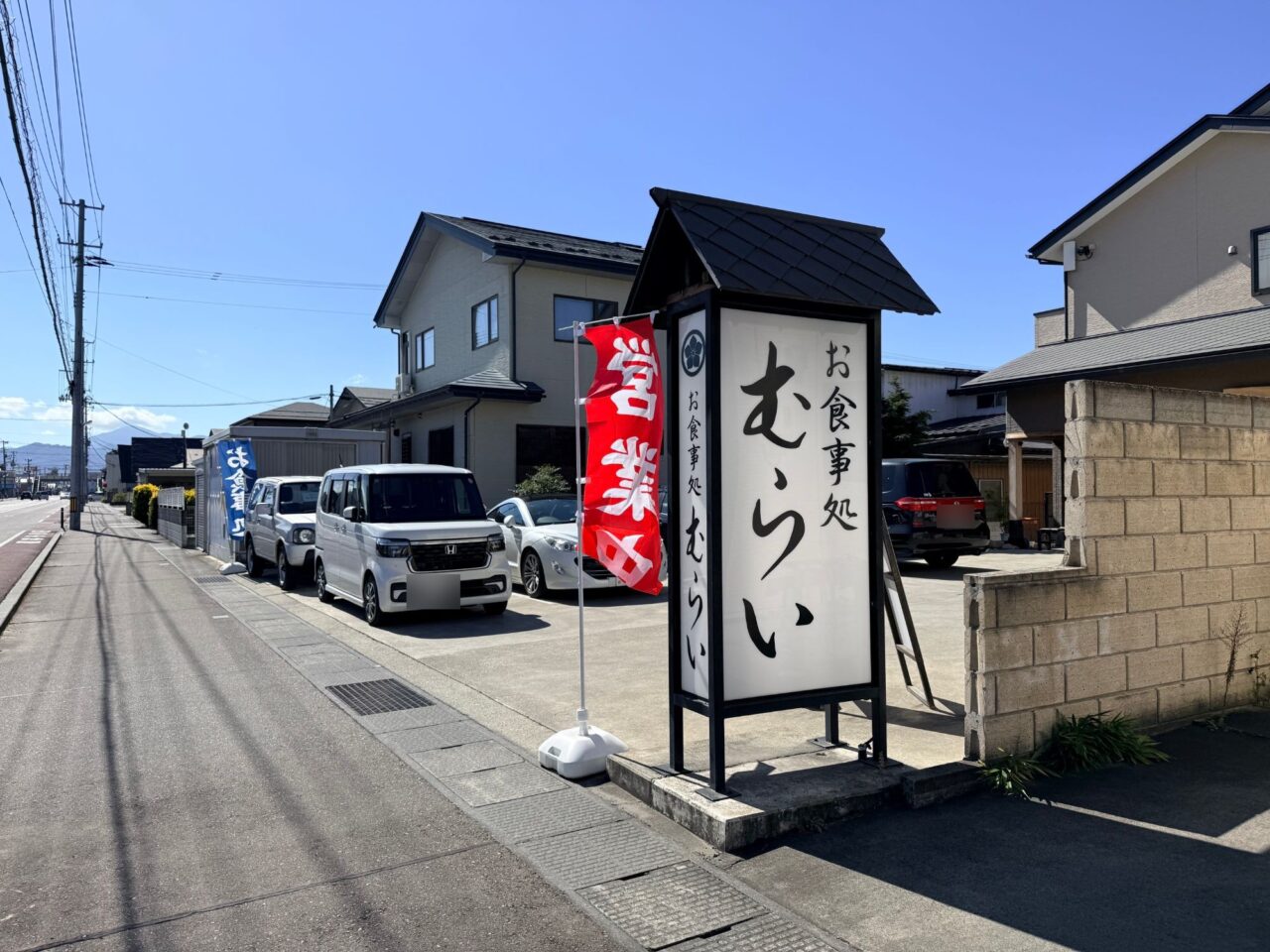 道路沿いに立つお食事処むらいの看板と営業中ののぼり