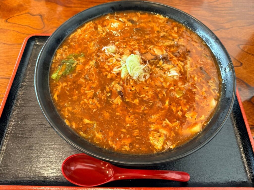 溶き卵と白菜が入った赤いスープのスーラー麺