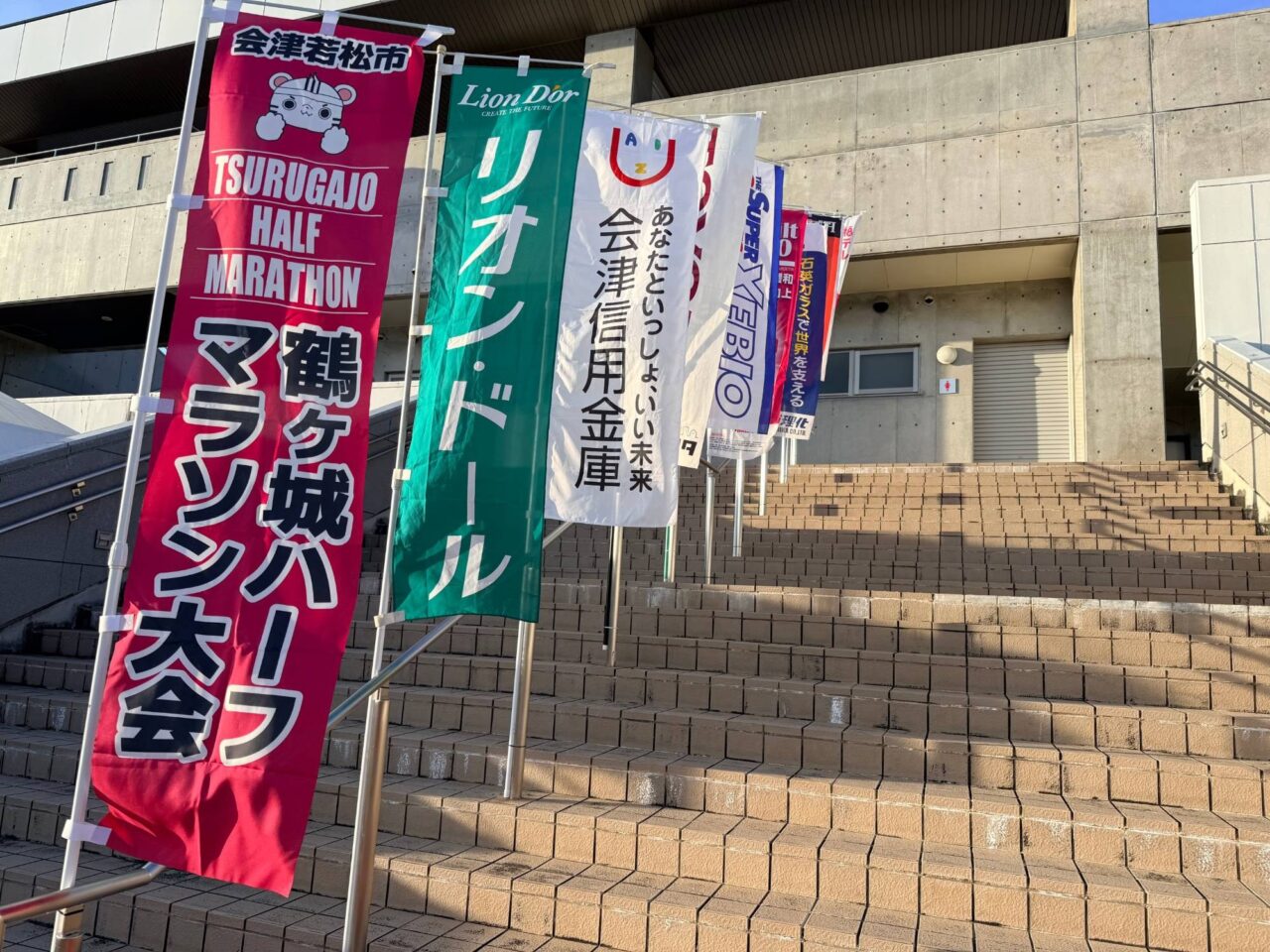 階段沿いに並ぶ鶴ヶ城ハーフマラソン大会と協賛各社ののぼり旗