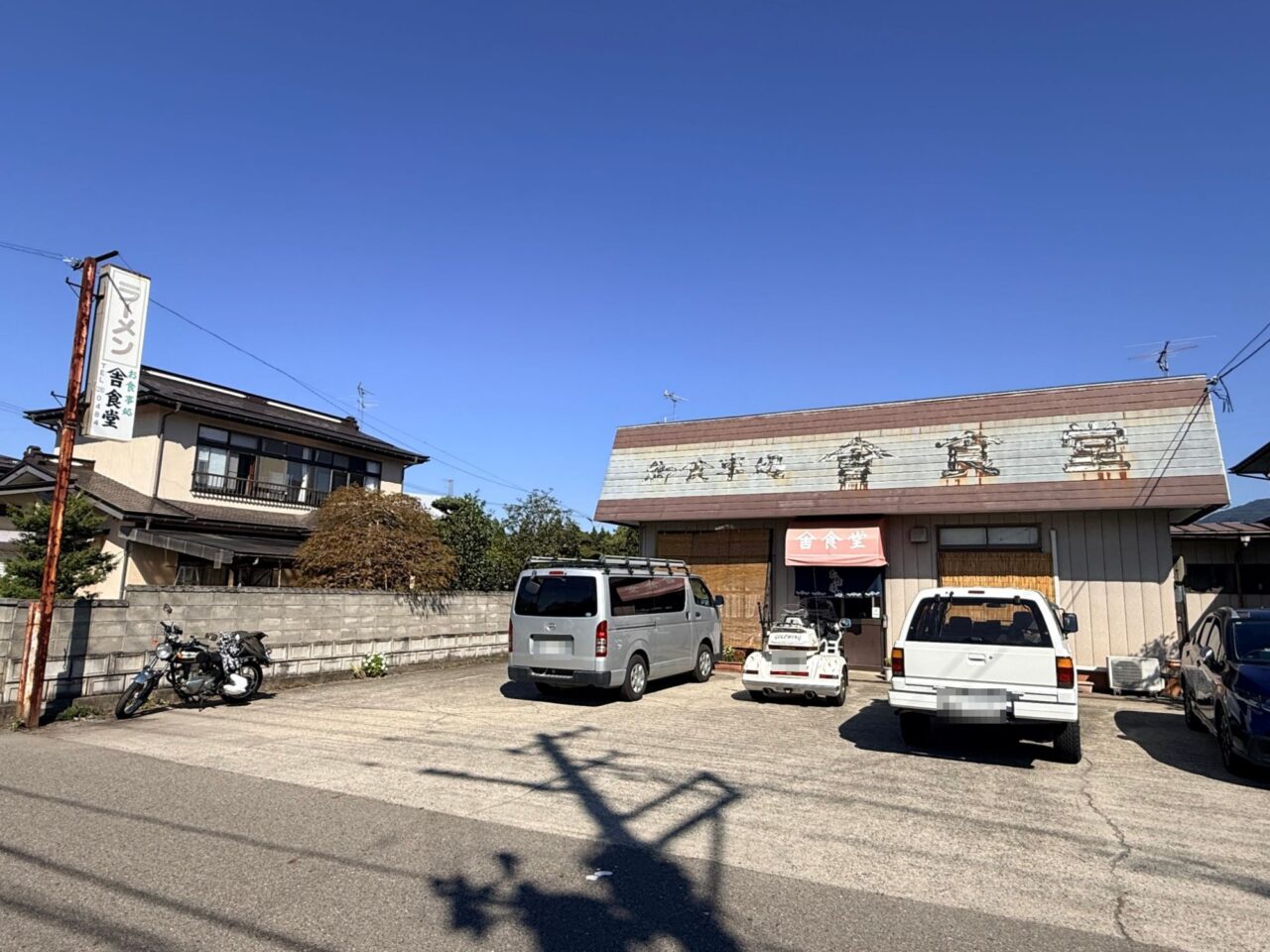 道路沿いに立つ舎食堂の看板と店舗の外観