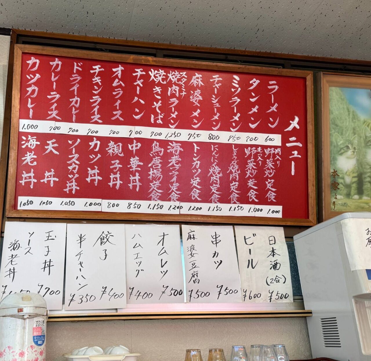 舎食堂の店内の壁に掲げられた赤いメニュー表と一品メニューの貼り紙