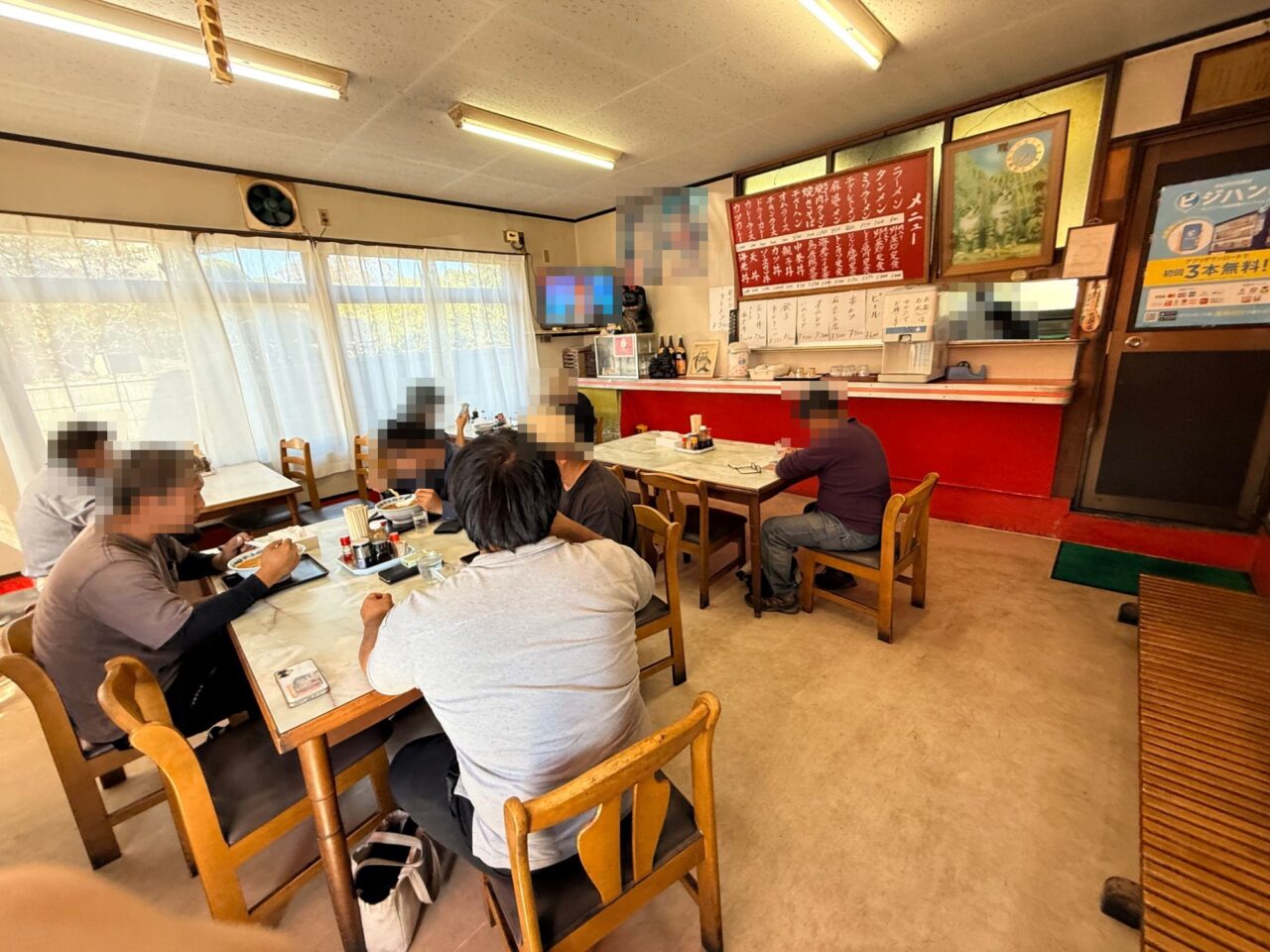テーブル席が並ぶ舎食堂の店内と壁の赤いメニュー表