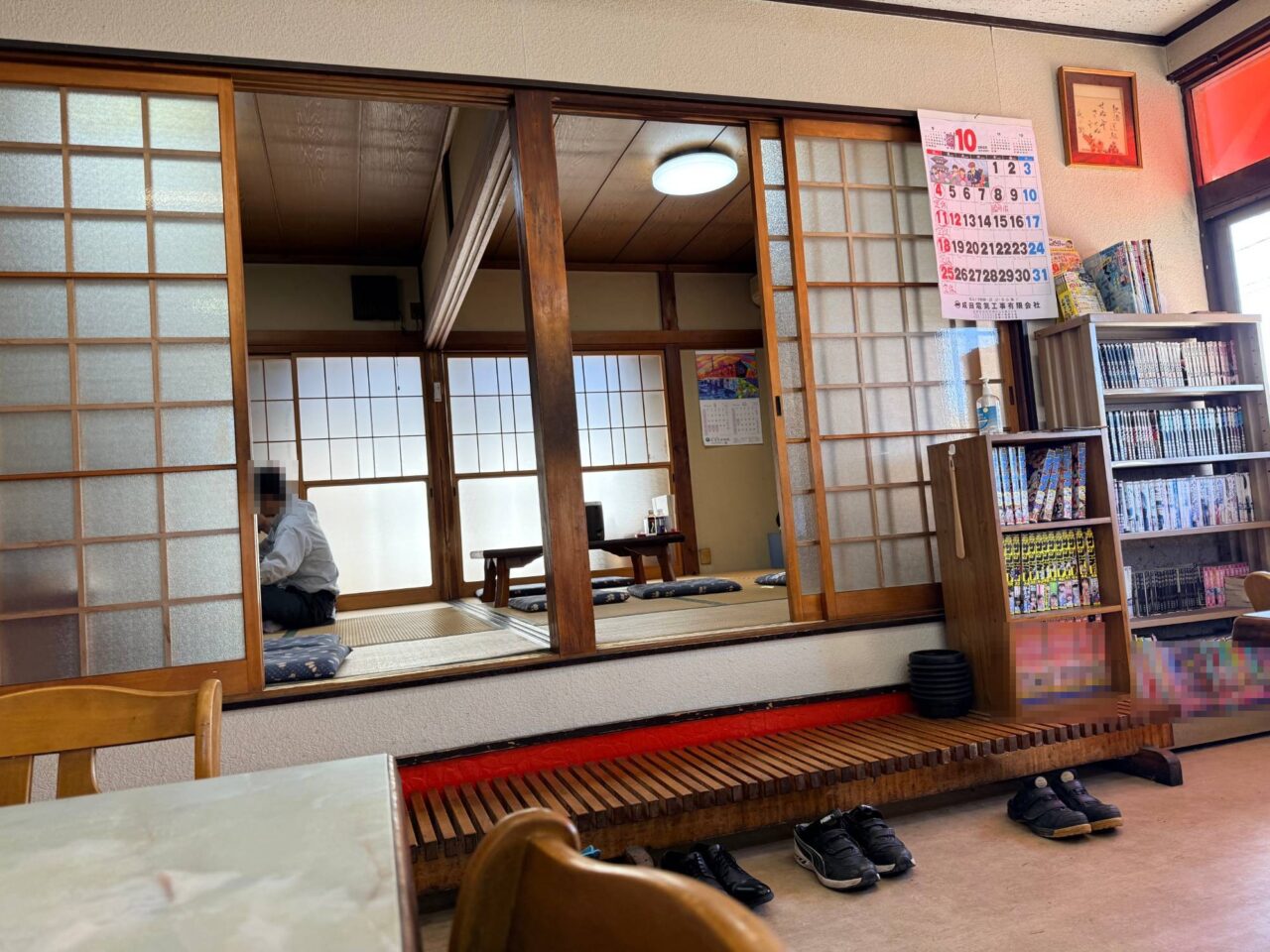 舎食堂の店内にある畳敷きの座敷席と漫画が並ぶ本棚